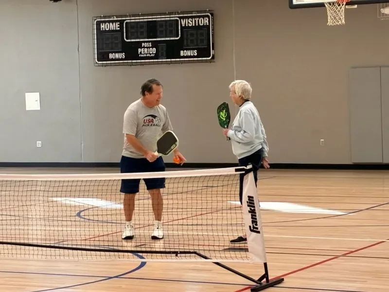 Coach Mark Boehm talking with a player at the net during a session
