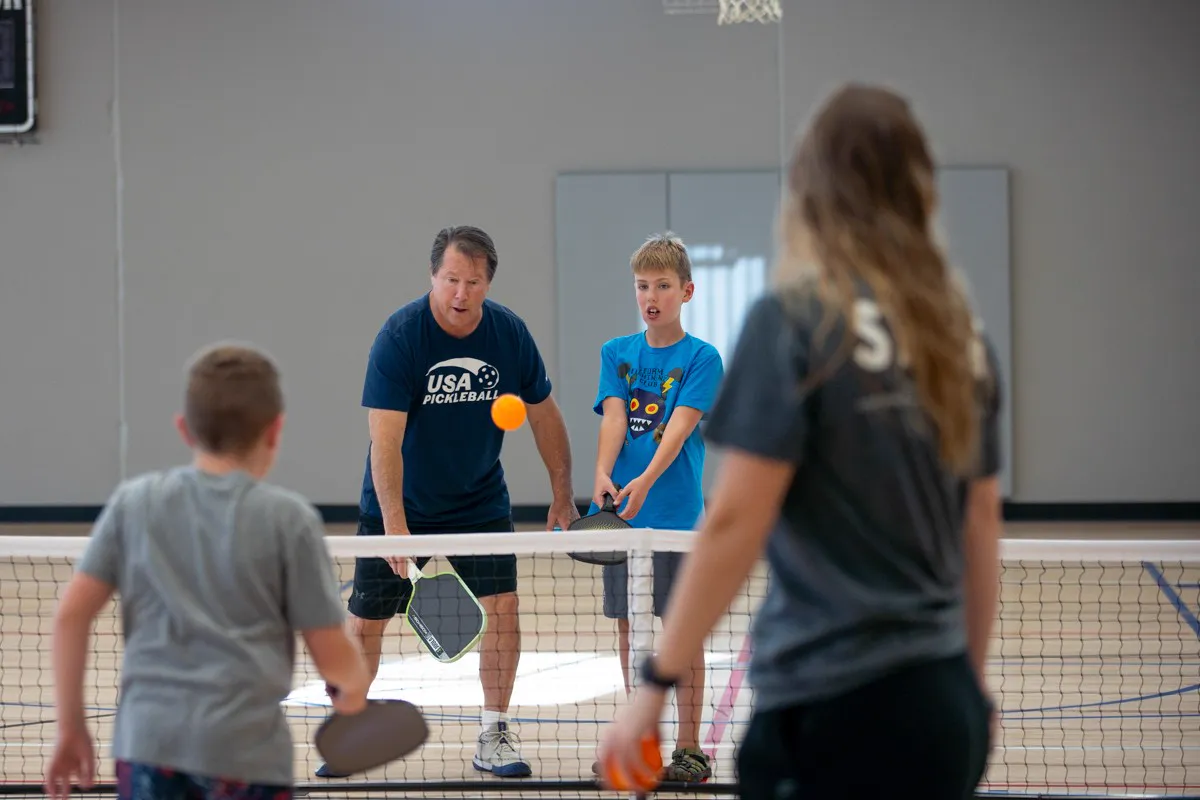 Coach Mark Boehm at the net with a young player, watching the ball during a drill