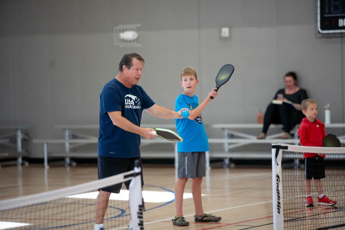 Coach Mark Boehm showing a young player how to hold the ball for a serve